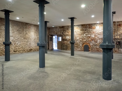 Industrial heritage interior; a renovated building with iron support columns, stone floors and large wooden beams.