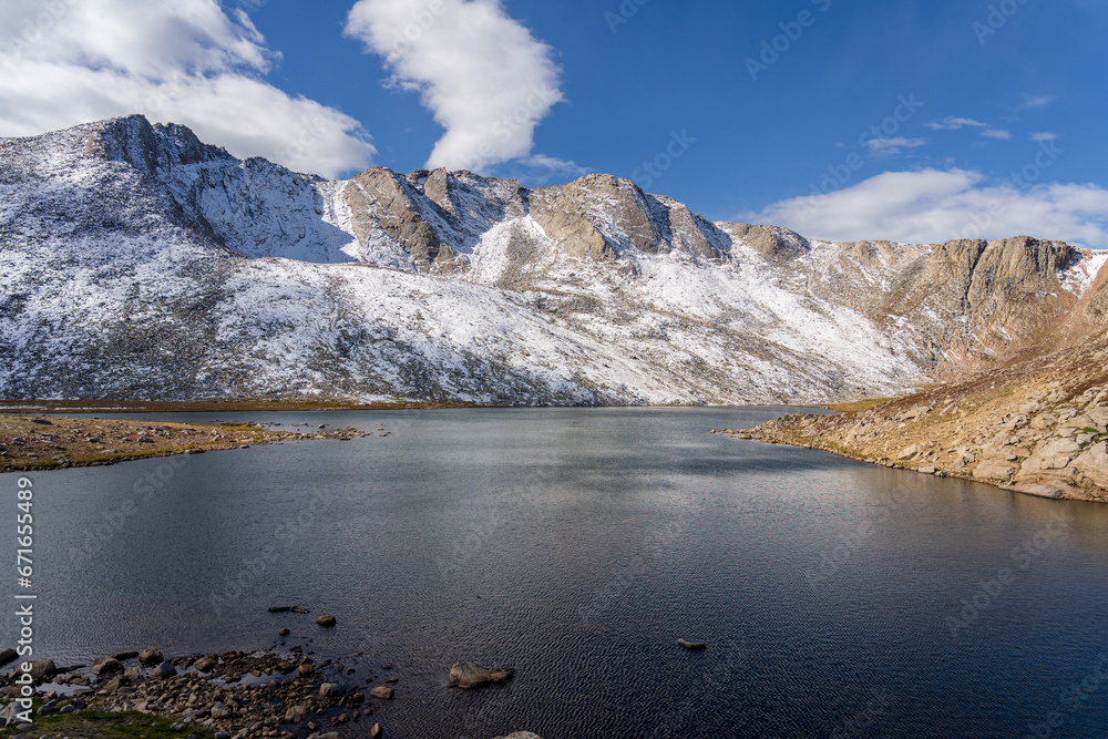 Obraz premium Snow covered mountain, water, and tundra at Summit Lake at Mount Evans/Mount Blue Sky near Idaho Springs, Colorado, on a sunny fall/winter day