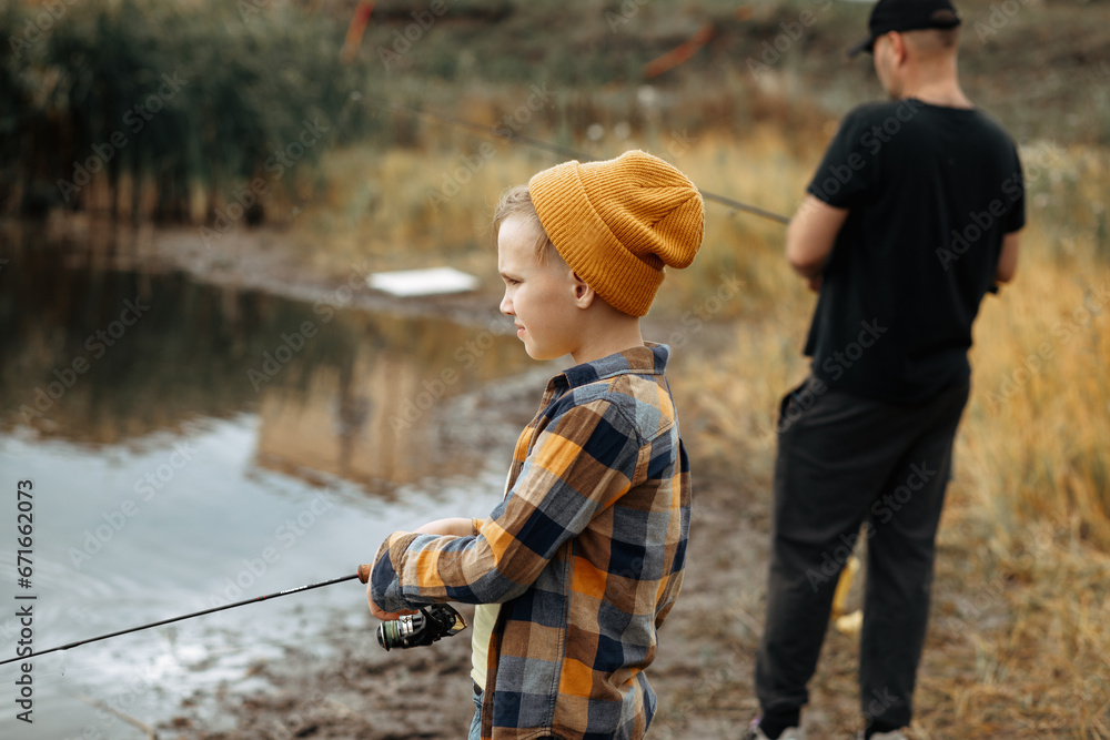 Kid teen boy catching a fish with dad in the lake, river or pond Kid teen boy catching a fish with dad in the lake, river or pond