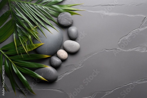 Top view of palm leaves and grey stones on a grey spa background  embodying the spa concept.