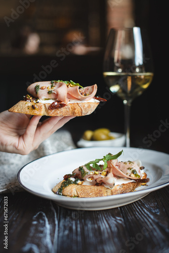 Appetizing bruschetta with thin pieces of meat on a dark background. Food photography.
