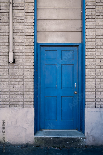 A bright blue door in a light cream colored brick building. 