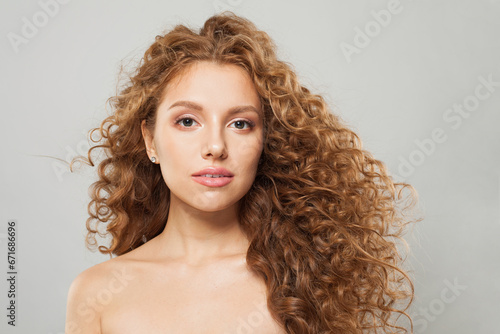 Pretty young wavy hair woman. Fashion model with long curly hairstyle and natural fresh clear skin posing on white background
