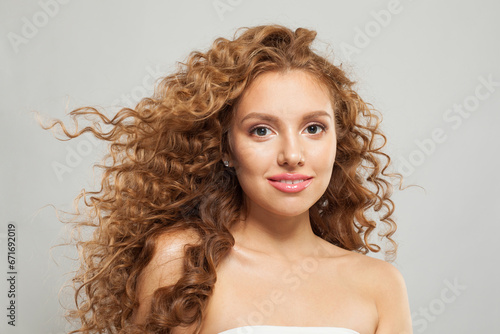 Young lovely woman redhead model with natural makeup, long healthy brown curly hair and cute smile looking at camera on white background. Hair care, hair treatment, wellness and cosmetology concept