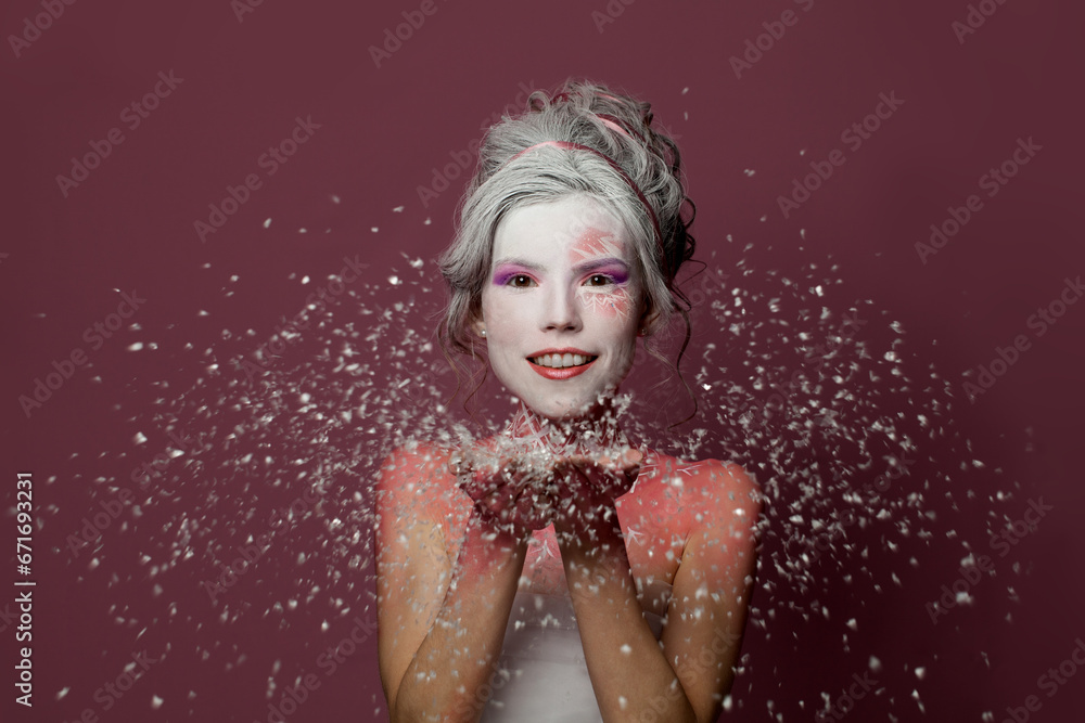 Beautiful woman with stage makeup and white snow on colorful pink background. Winter party, Halloween  carnival and theater concept