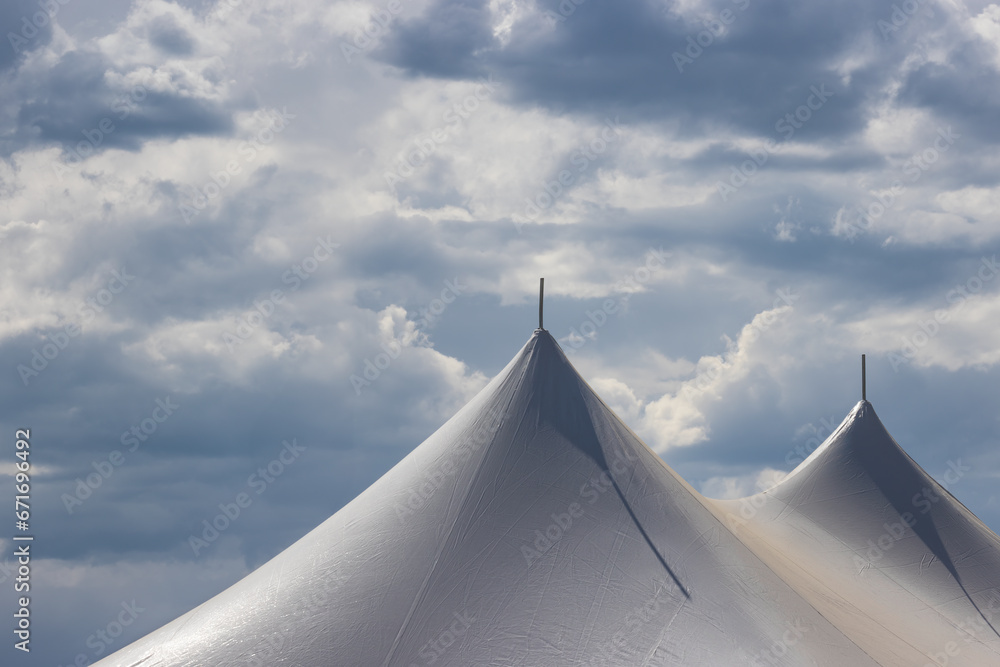 Cloudy skies surround the tops of these two tents.