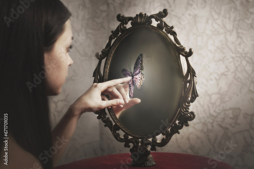 woman touches a surreal butterfly that appears in her mirror; concept of introspection and freedom