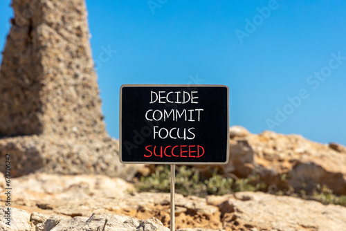 Decide commit focus succeed symbol. Concept word Decide Commit Focus Succeed on beautiful blackboard. Beautiful red stone blue sky background. Business decide commit focus succeed concept. Copy space.