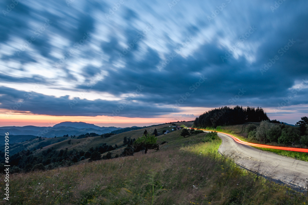 Light trails from a car on a mountain road at sunset