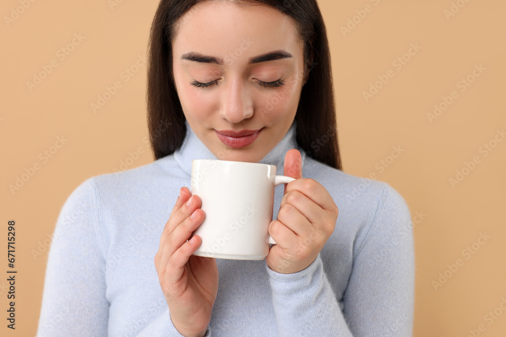Beautiful young woman holding white ceramic mug on beige background Beautiful young woman holding white ceramic mug on beige background