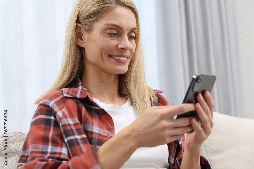 Happy woman sending message via smartphone at home Happy woman sending message via smartphone at home
