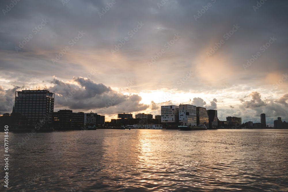 Storm clouds during sunset travel through the city of Amsterdam and give a dramatic atmosphere. Dutch lifestyle and modern city scenery