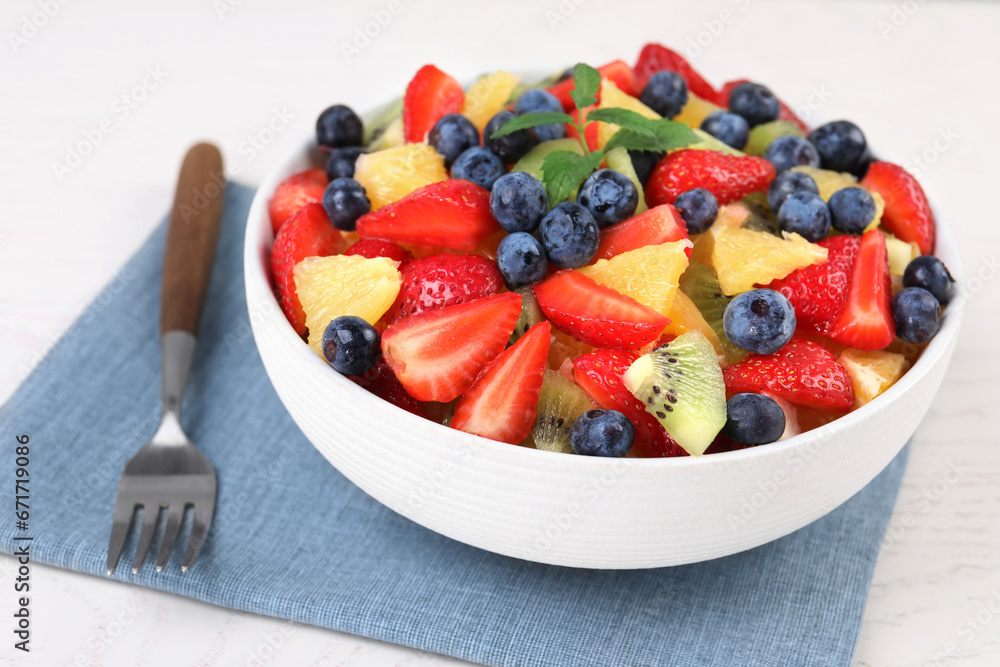 Delicious fresh fruit salad in bowl served on white table, closeup Delicious fresh fruit salad in bowl served on white table, closeup