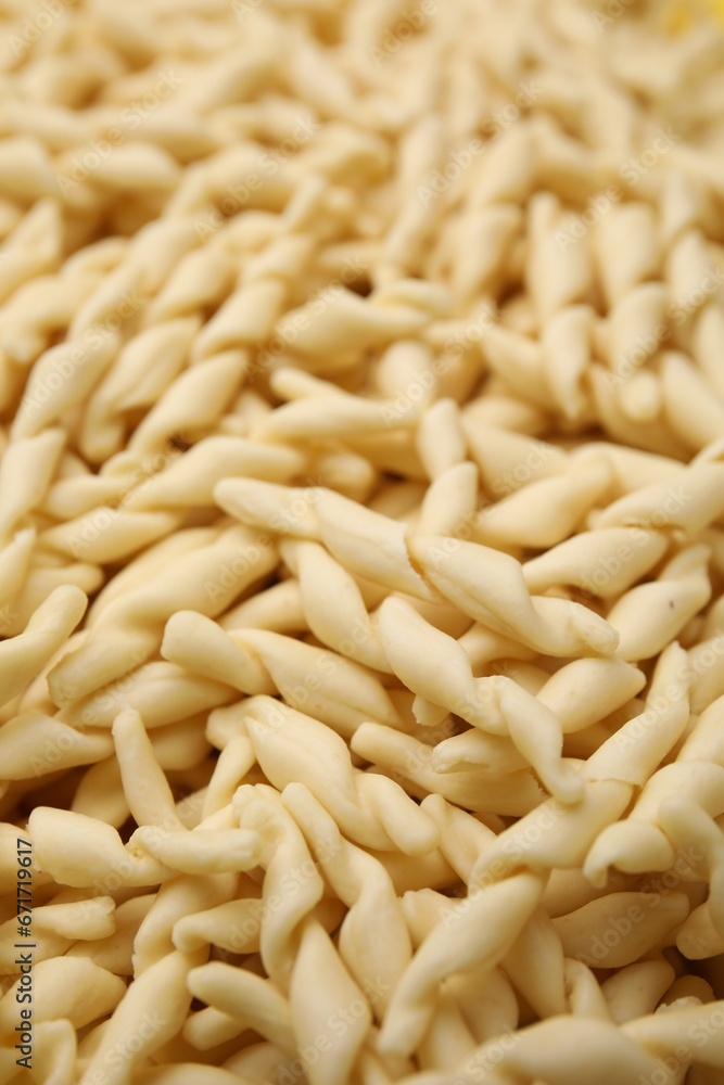 Uncooked trofie pasta as background, closeup view Uncooked trofie pasta as background, closeup view