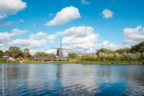 Historic wooden windmill on the banks of a river near Haarlem, in the west of the Netherlands. Dutch scenery on a sunny day