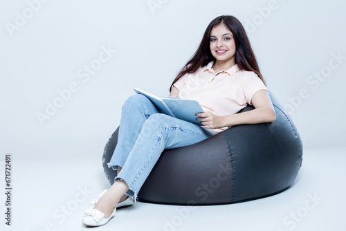 indian latin Female sitting on bean bag With Book and relaxing,
