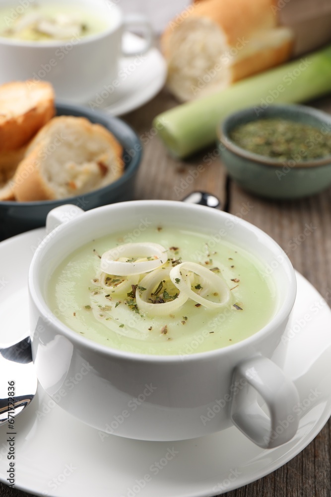 Delicious cream soup with leek and spices in bowl on wooden table, closeup Delicious cream soup with leek and spices in bowl on wooden table, closeup