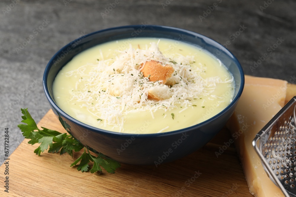 Delicious cream soup with parmesan cheese and croutons in bowl on grey table, closeup Delicious cream soup with parmesan cheese and croutons in bowl on grey table, closeup