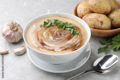 Delicious cream soup with soy sauce and parsley served on light grey marble table