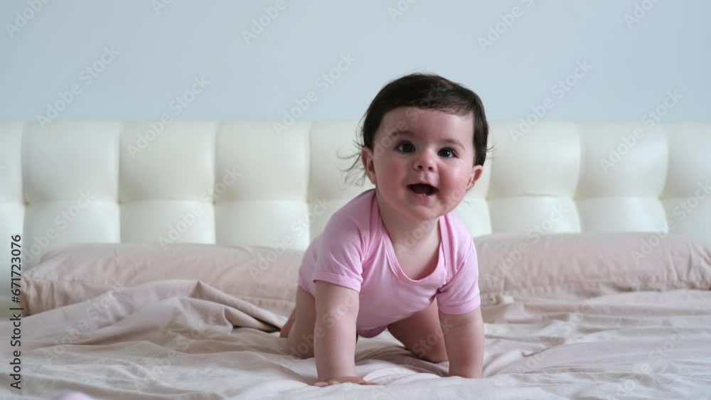 smiling healthy baby in pink bodysuit crawling on bed smiling healthy baby in pink bodysuit crawling on bed