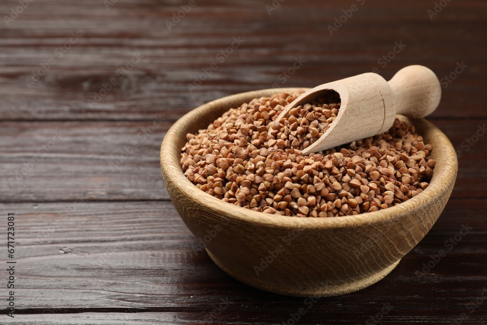 Bowl and scoop with dry buckwheat on wooden table, closeup. Space for text Bowl and scoop with dry buckwheat on wooden table, closeup. Space for text