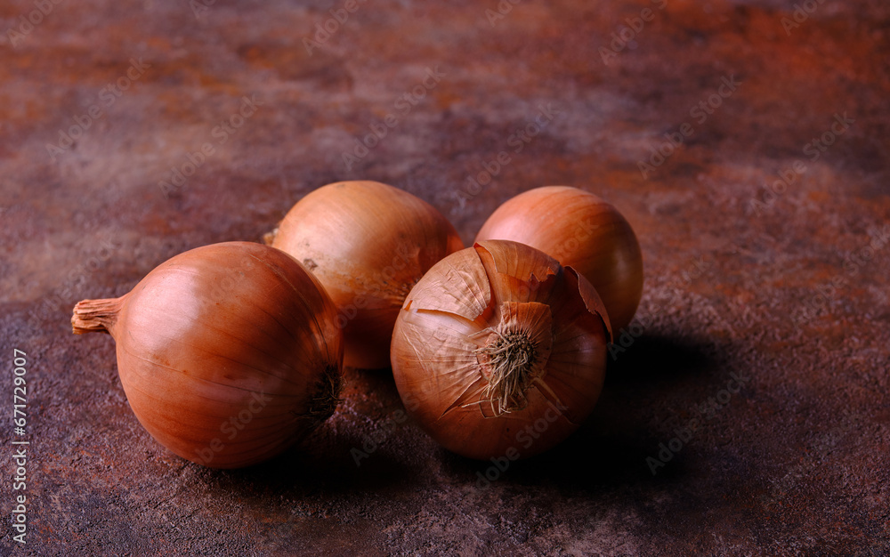 Large natural-looking onions with peels lie on a textured rusty surface. Selective focus Large natural-looking onions with peels lie on a textured rusty surface. Selective focus