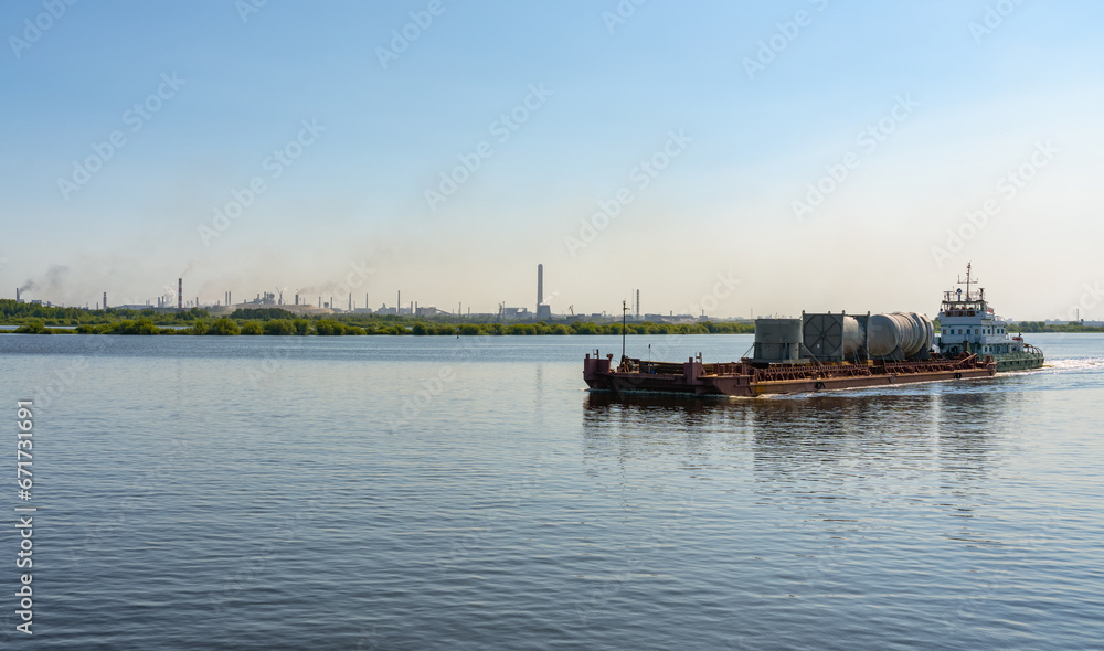 A barge carries cargo along the Sheksna River against the backdrop of the Cherepovets Metallurgical Plant