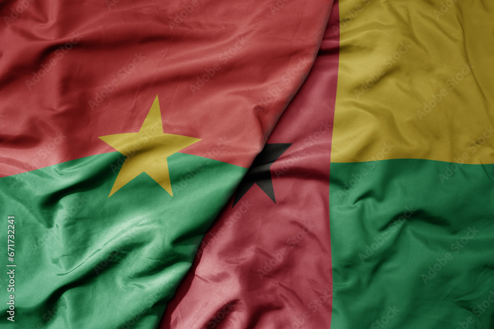 big waving national colorful flag of burkina faso and national flag of guinea bissau .