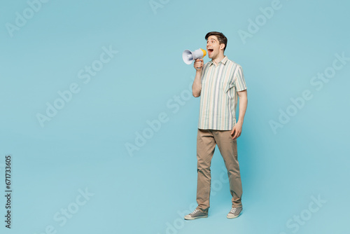 Full body side view young man wears striped shirt casual clothes hold in hand megaphone scream announces discounts sale Hurry up isolated on plain pastel light blue cyan background. Lifestyle concept.