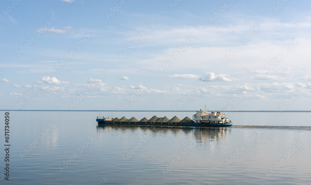 A dry cargo barge sails on Lake Beloe in complete calm