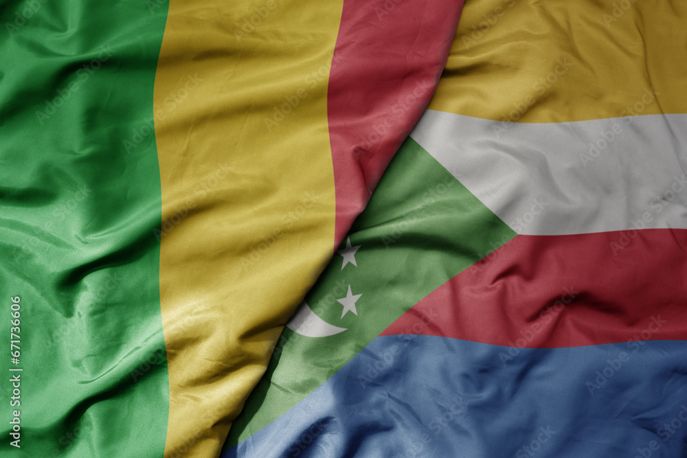 big waving national colorful flag of mali and national flag of comoros .