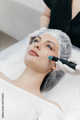 Shot of a beautiful young woman on a facial dermapen treatment at the beauty salon. Dermatologist in medical gloves doing hydro peeling procedure. Close up facial treatment. 