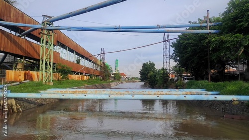 Blue metal pipe crossing river from factory to another area of it