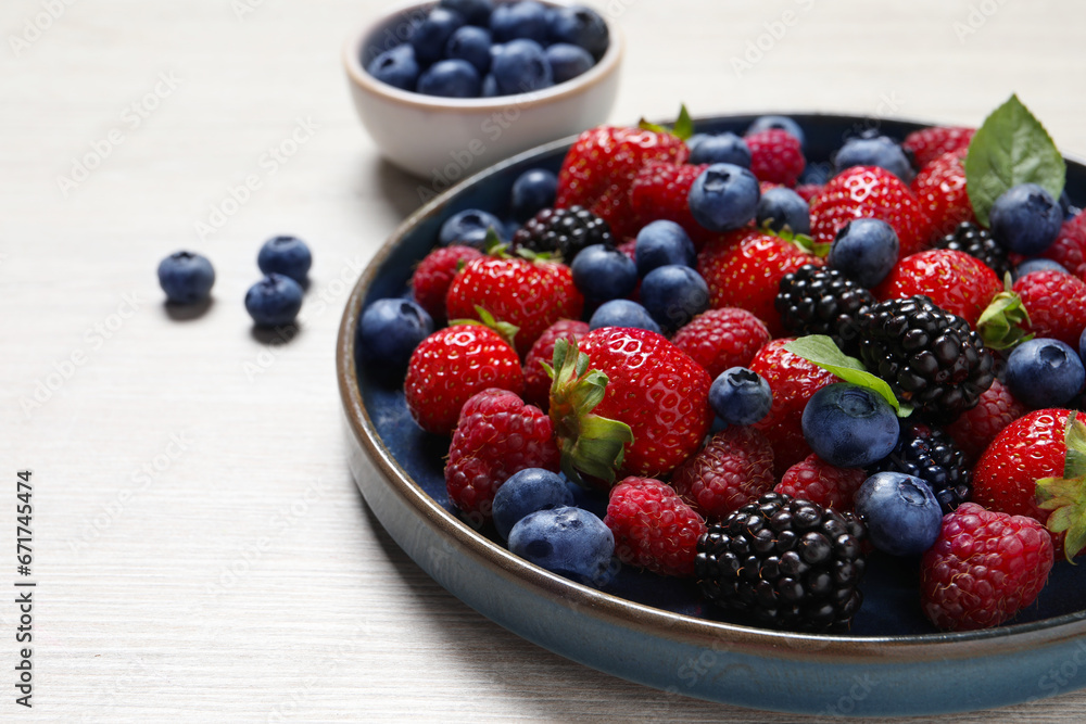 Different fresh ripe berries on light wooden table, closeup. Space for text Different fresh ripe berries on light wooden table, closeup. Space for text
