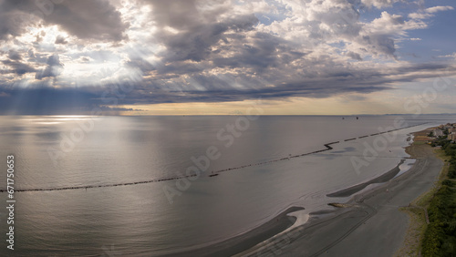 Aerial view of sandy beach and stormy sky with sun rays piercing the clouds  flat sea at dawn  Italy