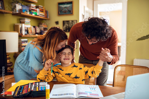 Loving parents comforting their son during study time in a cozy home environment photo