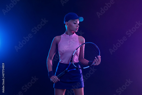 Tennis player woman with racket on tournament. Girl athlete with tenis racket on court with neon colors. Sport concept. Download a high quality photo for design of a sports app or tour events. © Mike Orlov