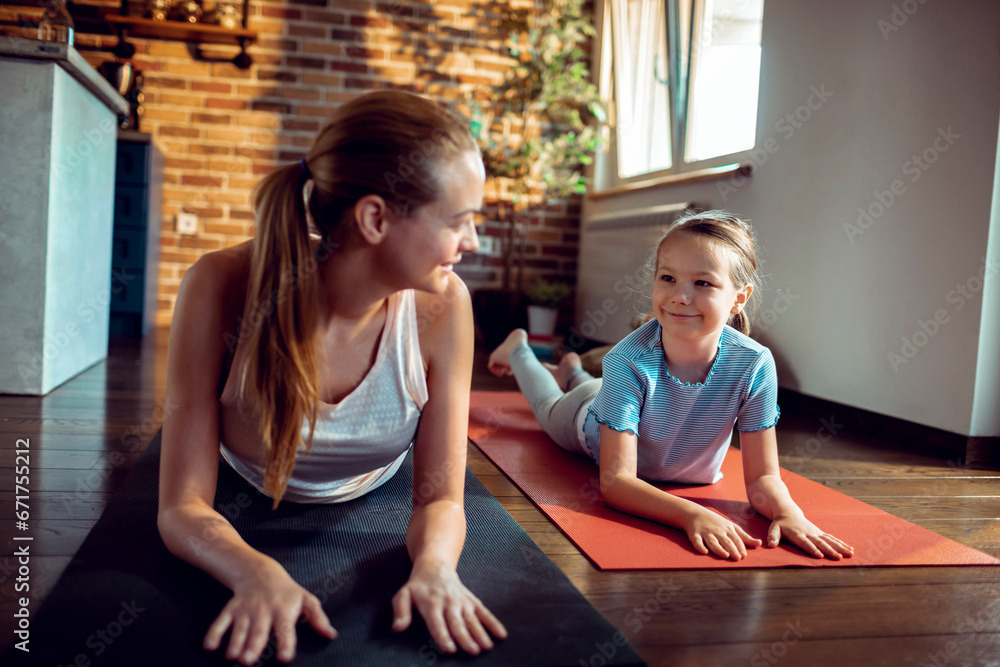 Supportive mother guiding her daughter through a yoga pose Supportive mother guiding her daughter through a yoga pose