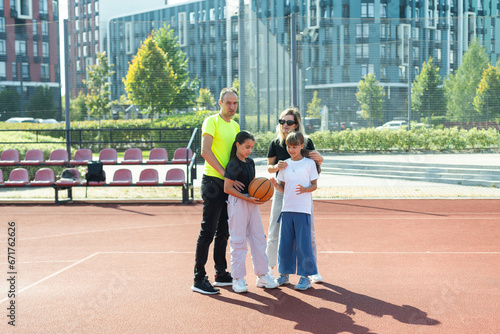summer holidays, sport and people concept - happy family with ball playing on basketball playground © Angelov