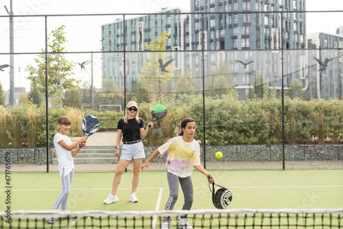Cheerful coach teaching child to play tennis while both standing on tennis court © Angelov