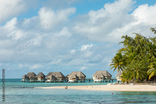 French Polynesia Tikehau atoll with pink coral reef lagoon and overwater bungalows.