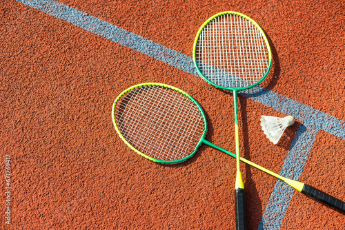 Badminton shuttlecocks and racket, placed in the corner of a synthetic field. © Angelov