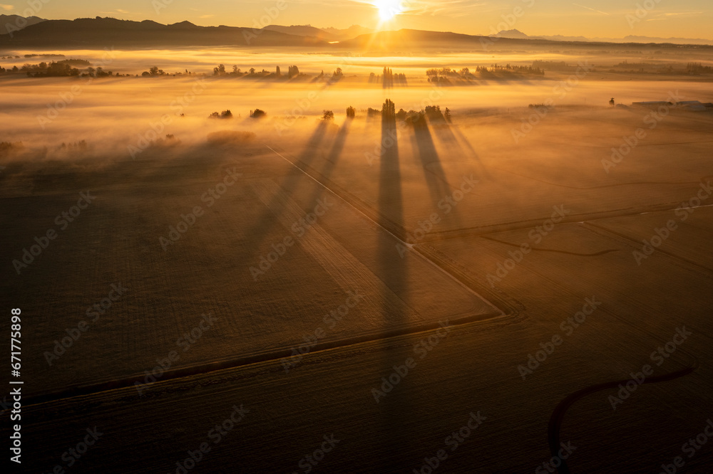 Dramatic sunrise over rural farmland with ground fog adding atmosphere. Morning in the Skagit Valley is an almost magical event as the color and texture make for a beautiful landscape. Washington, USA - obrazy, fototapety, plakaty 