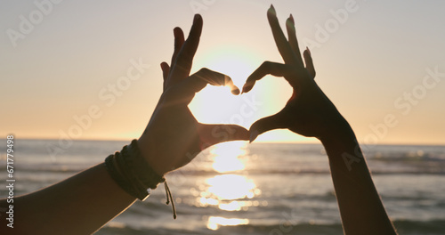Love, hands and heart on beach with sunset, water background and horizon for vacation, travel or adventure. People, man and woman by ocean or sea with emoji for romance, care and relationship on trip