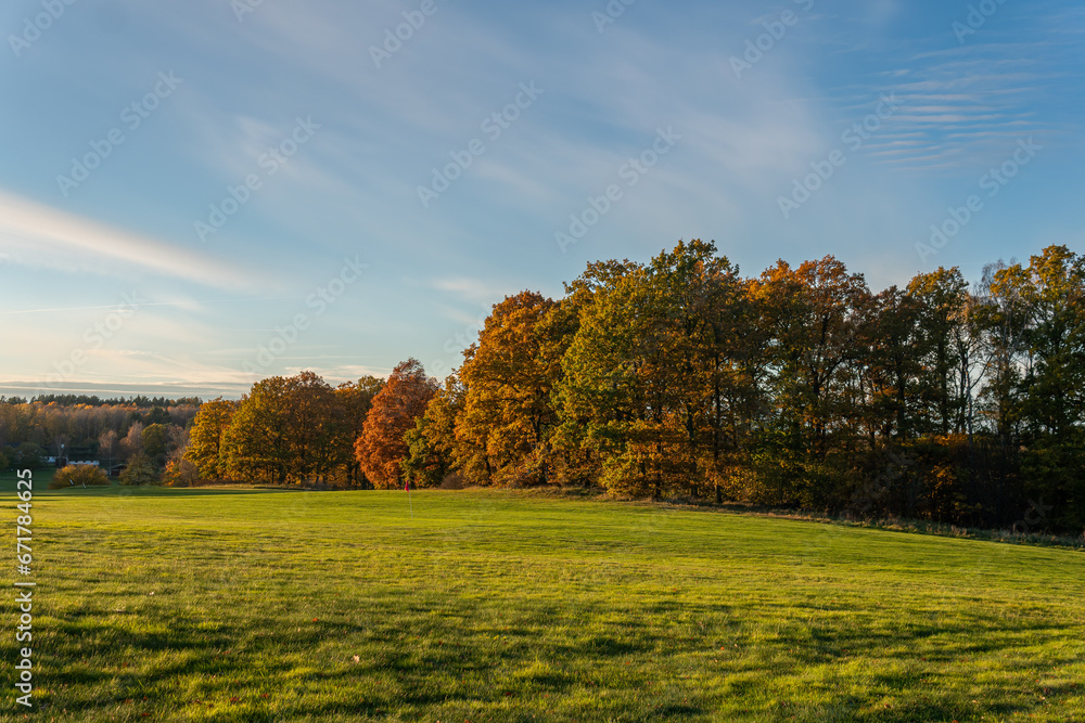 Golf course during autumn. Beautiful nature, green grass and multicolored trees. Symbol of autumn. 