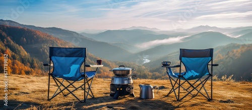 Active travel concept with two blue camping chairs gas burner kettle stand amidst beautiful autumn mountains photo