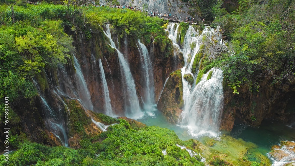 Obraz premium Tourists visit famous Plitvice waterfalls in Croatia. Mountain streams flow into a lake with azure clear water. Summer National Park.