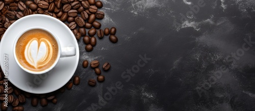 Top view of a ceramic cup filled with black coffee and milk foam accompanied by a napkin and a sack of roasted coffee beans on a dark table