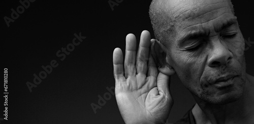 deaf man suffering from deafness and hearing loss on grey black background with people stock image stock photo © herlanzer