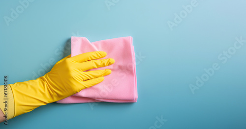 Cleaning concept: glove-clad hand gripping a pink rag against a turquoise backdrop.